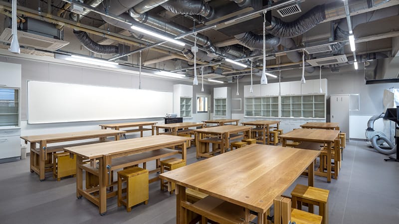 義肢装具実習室の内部、木製の作業台が並ぶ広々とした教室の様子。