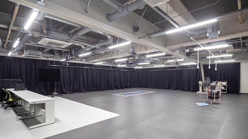 運動学実習室の広々とした室内、黒いカーテンと照明が特徴的。