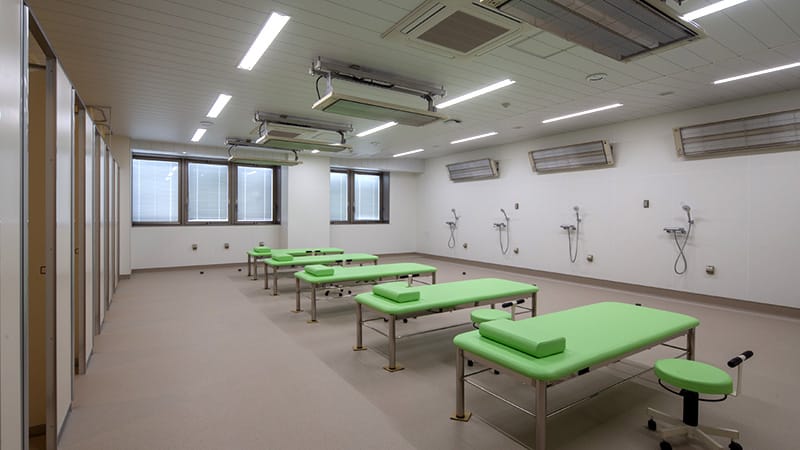 水治療法実習室の内部、緑の施療台が並ぶ明るい空間。