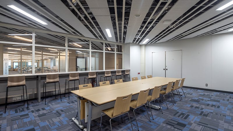 駅前キャンパスの学生スタディルーム8C、広々としたテーブルと椅子が配置された明るい室内。