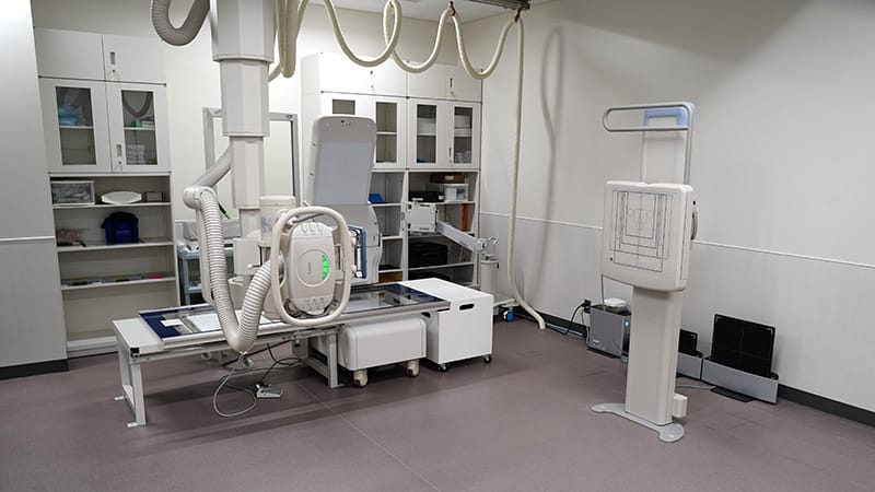 X線撮影室の内部、医療機器や収納棚が整然と配置されている様子。
