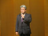 福島県立医科大学のサマーセミナーで講演する男性がマイクを持って話している様子。