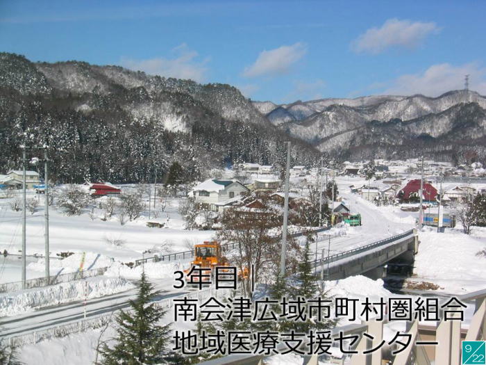 地域医療支援センターがある雪景色の風景、山々と住宅が見える。