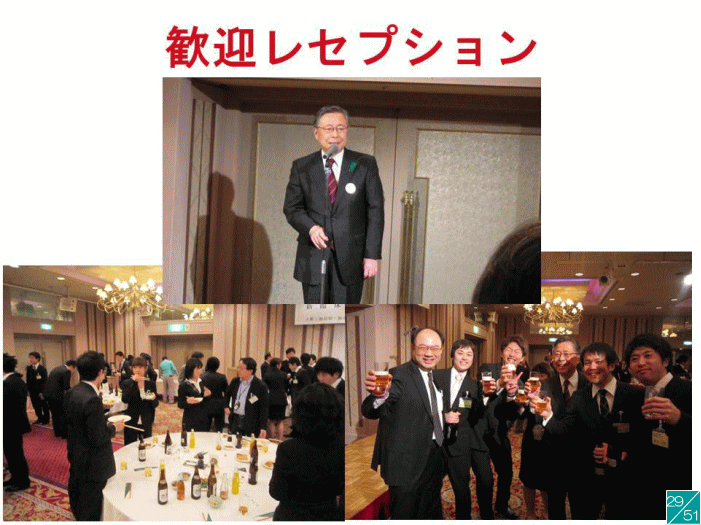 歓迎レセプションの様子。スーツを着た男性がスピーチをしており、周囲には参加者が集まり、飲み物を持っている。