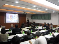 福島県立医科大学の講義室で、プレゼンテーションを行う講師と聴衆の様子。