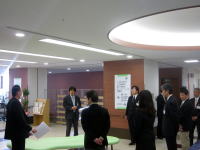 福島県立医科大学の施設内で、スーツを着た複数の人々が集まり、説明を受けている様子。