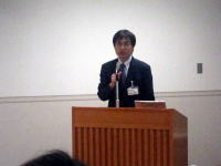 福島県立医科大学の講演会で話す男性がマイクを持っている様子。
