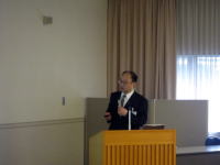 福島県立医科大学で講演を行う男性が、スライドを指し示している様子。