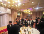 福島県立医科大学のイベントで、スーツを着た参加者たちがテーブルを囲んで談笑している様子。