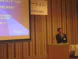 福島県立医科大学の講演会で話す男性とプレゼンテーションのスライド。