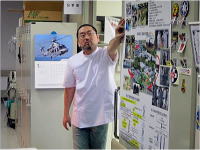 災害医療研修の一環として、資料を指し示す医療従事者の姿。背景には関連情報が掲示されている。