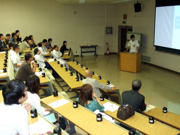 セミナーで講演を行う講師と、聴衆が座っている教室の様子。