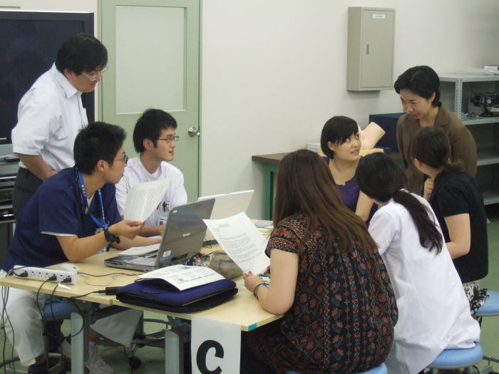 セミナーでディスカッションを行う医学生たちの様子。テーブルには資料やノートパソコンが置かれ、活発な意見交換が行われている。