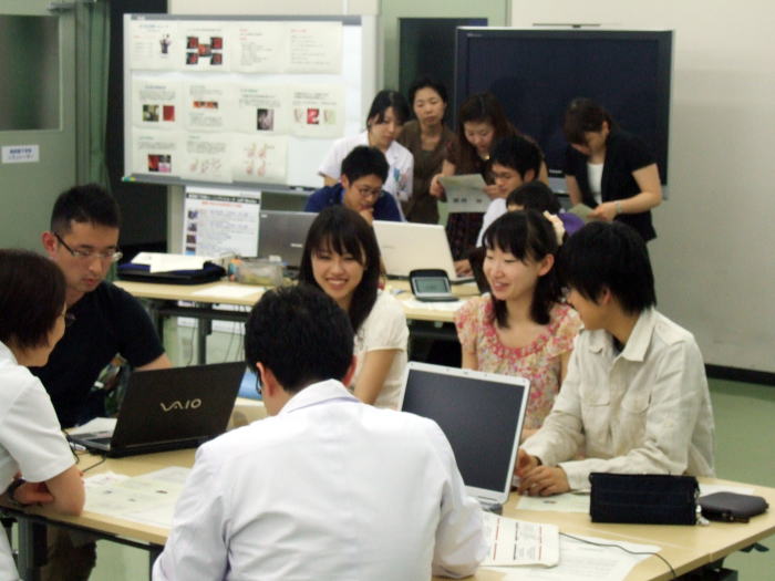 セミナーでディスカッションを行う学生たちの様子。テーブルにはノートパソコンや資料が並び、活発な意見交換が見られる。