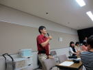 医療系セミナーで講演を行う男性がマイクを持ち、参加者に向けて話している様子。