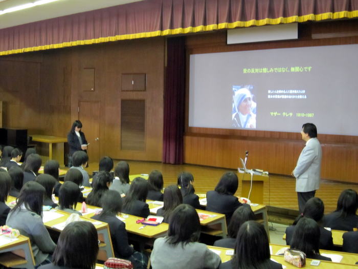 出前講座で桜の聖母学院高等学校の生徒たちが講演を聴いている様子。講師がスクリーンを指し示しながら説明している。