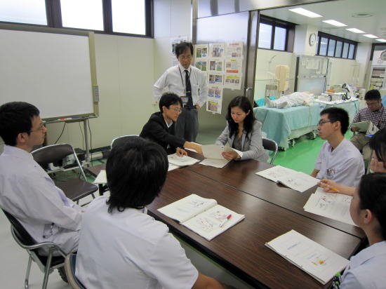 医学生たちがテーブルを囲んでディスカッションを行っている様子。背景には医療機器が見える。