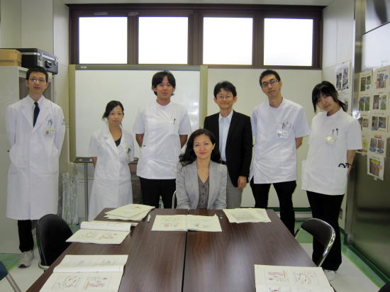 福島県立医科大学のセンターで、白衣を着た医療スタッフとZhanat Carr氏が一緒に写っている写真。テーブルには資料が広げられている。