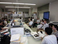 医療関連の会議が行われている福島県立医科大学の研究室の様子。多くの人が集まり、資料を見ながら議論している。