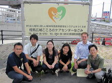 相馬広域こころのケアセンターなごみの前で、6人の人々が笑顔で座っている様子。