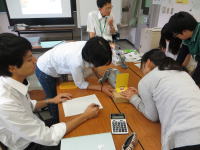 学生たちがテーブルを囲んでグループ活動を行い、資料を見ながら議論している様子。