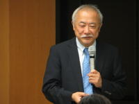 福島県立医科大学で講演を行う男性がマイクを持って話している様子。