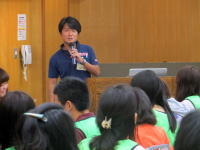 講演を行う男性と、緑の服を着た聴衆が集まる福島県立医科大学のイベントの様子。