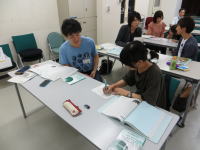 学生たちがテーブルを囲んで話し合い、資料に目を通している様子。