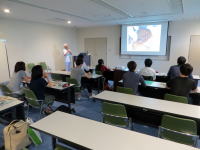 医療に関する講義を受ける参加者たちが、スクリーンに映る資料を見つめている様子。