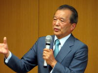 福島県立医科大学で講演を行う男性がマイクを持って話している様子。