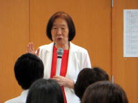 福島県立医科大学で講演を行う女性がマイクを持ち、聴衆に向かって話している様子。