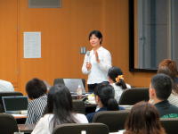 医科大学の講義で話す女性講師と、聴講する学生たちの様子。