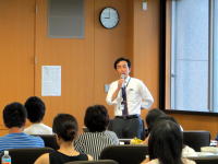 福島県立医科大学の講義中、講師が話している様子と聴衆の後ろ姿。