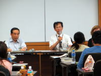 福島県立医科大学の講義中、講師がマイクを持って話している様子。参加者が聴講している。