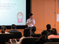 医療に関する講演を行う講師と、聴衆が座っている様子。