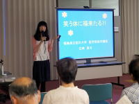 福島県立医科大学の講演会で、女性がプレゼンテーションを行っている様子。背景には「笑うことに福来る!!」と書かれたスライドが映し出されている。