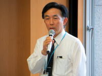 福島県立医科大学で講演を行う男性がマイクを持って話している様子。