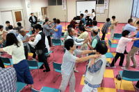 福島県立医科大学のイベントで、参加者が椅子を使って体を動かしている様子。