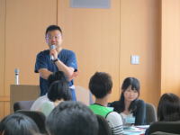 福島県立医科大学の講義中、講師がマイクを持って話している様子。学生たちが聴講している。