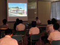 講義を受ける学生たちとスクリーンに映し出された建物の画像。
