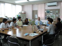 福島県立医科大学の会議室で、数人の学生と教員がテーブルを囲んで話し合っている様子。