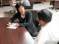 医療に関する会議で意見を交わす二人の専門家が、テーブルを挟んで話し合っている様子。