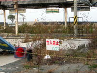 立入禁止の看板がある荒れた駅の跡地、周囲には雑草が生い茂っている。