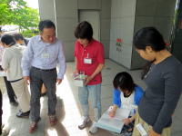 福島県立医科大学の前で、数人の人々が資料を見ながら話し合っている様子。