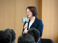 福島県立医科大学で講演を行う女性がマイクを持ち、聴衆に向かって話している様子。