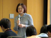 福島県立医科大学で講演を行う女性がマイクを持ち、聴衆に向かって話している様子。