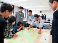 福島県立医科大学でのブレインストーミングセッション、参加者が問題点を議論しながら付箋を使ってアイデアを整理している様子。