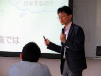 福島県立医科大学で講演を行う男性が、聴衆に向けて放射線の健康影響について説明している様子。