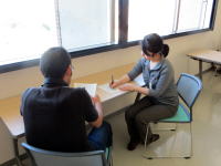 学生が机に向かって話し合いをしている様子。窓から自然光が差し込む明るい教室。