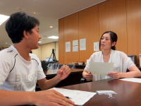 医療現場でのカウンセリング中の男性と女性、テーブルには書類が置かれている。